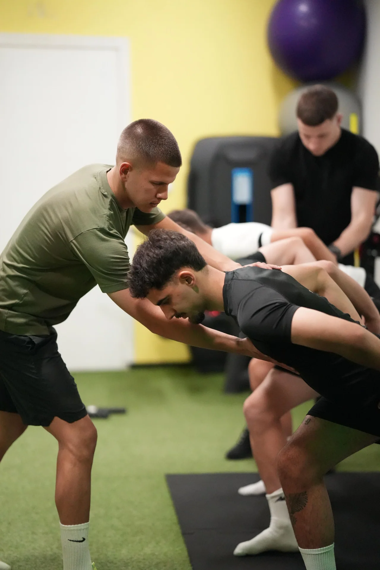 A coach guides an athlete through a controlled movement.