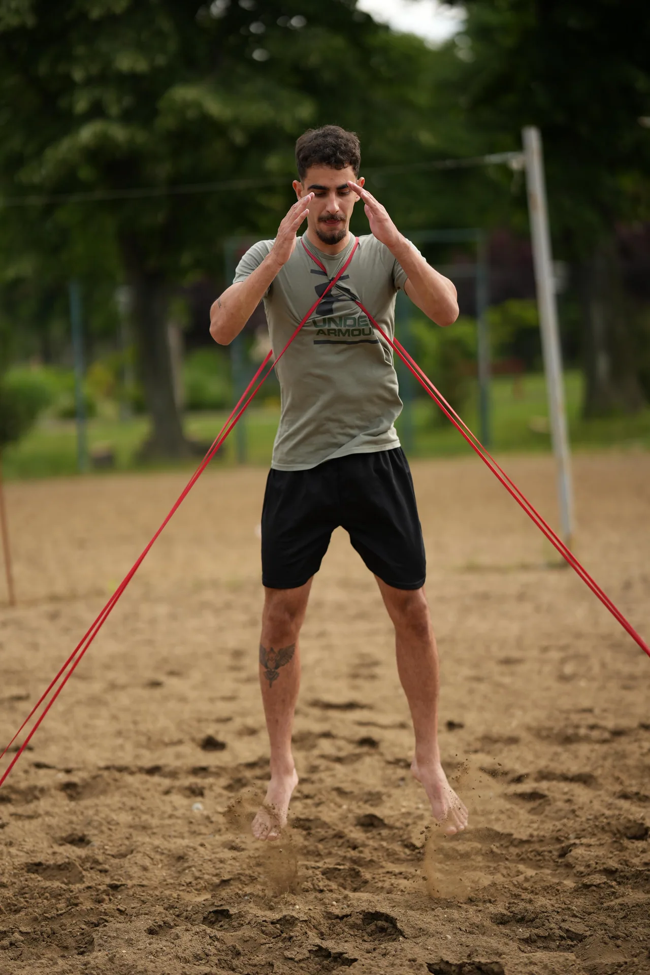 An athlete performs an outdoor explosive-power drill with resistance bands.