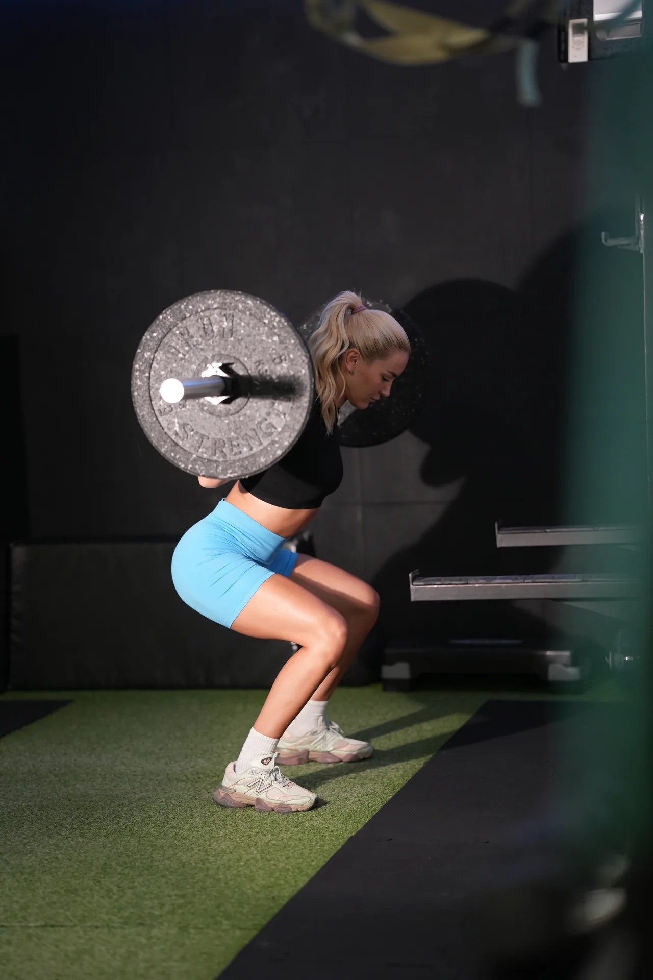 A member performs a barbell squat in the Academy training zone.