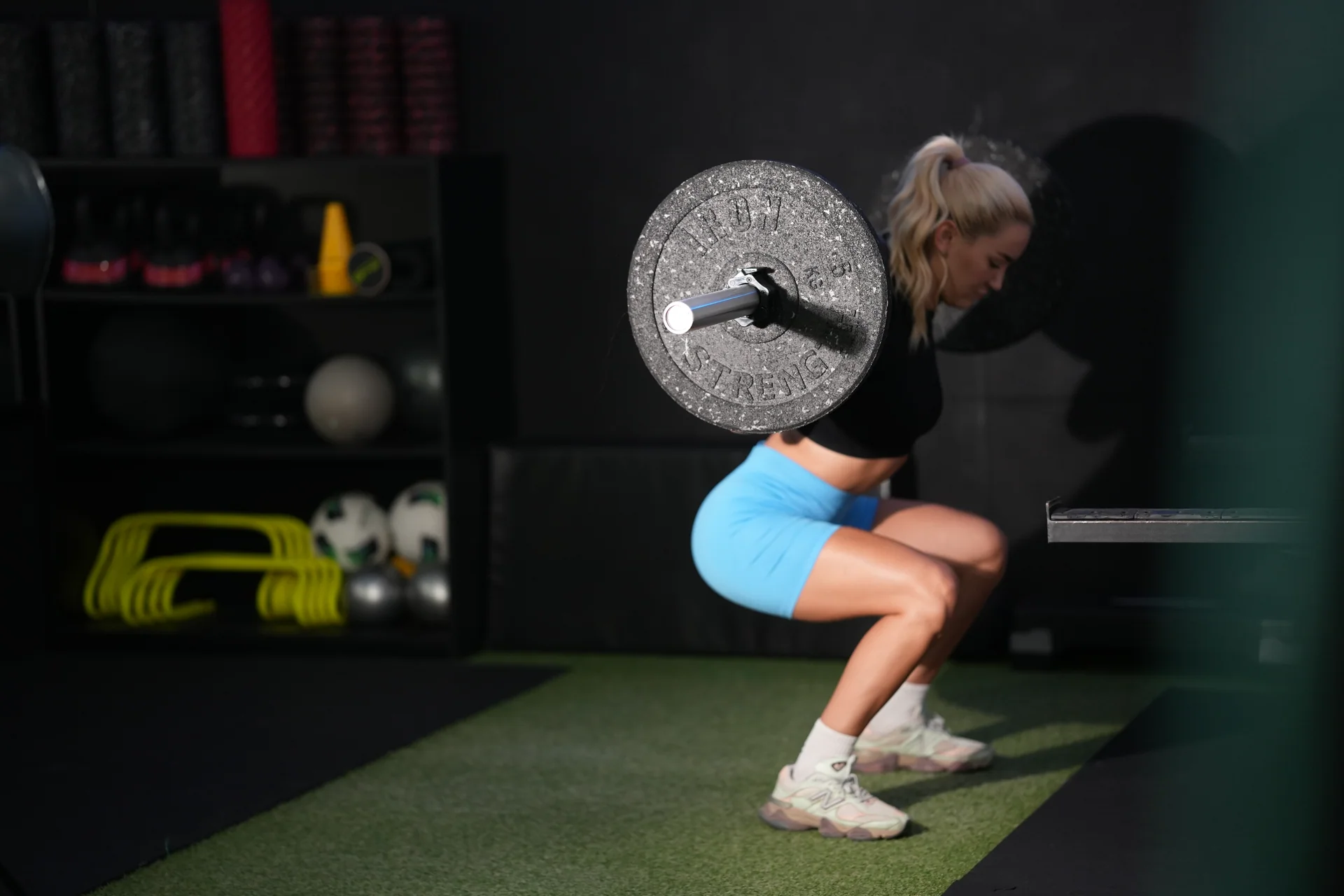 A member performs a barbell squat in the Academy training zone.